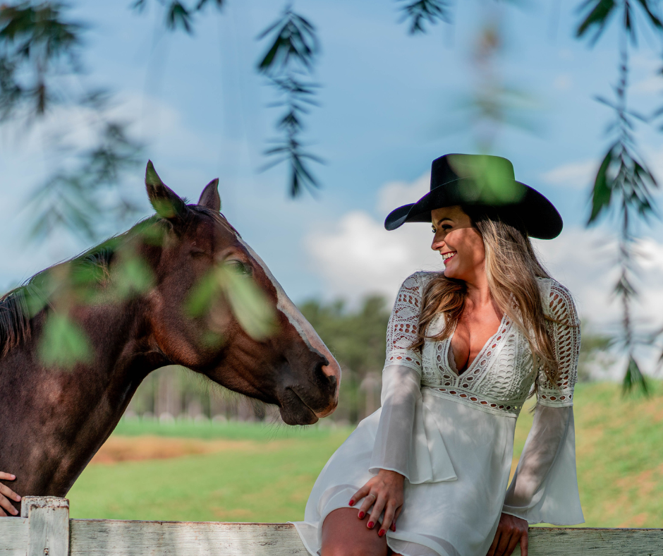 cowgirl sitting on the Fence Beside a Horse